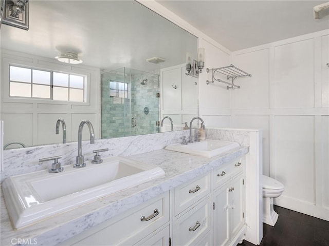 bathroom featuring a shower with door, vanity, wood-type flooring, and toilet