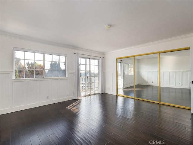 unfurnished room with ornamental molding and dark wood-type flooring