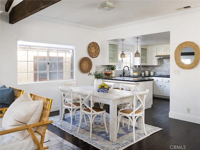 dining space featuring crown molding, dark hardwood / wood-style flooring, sink, and beamed ceiling