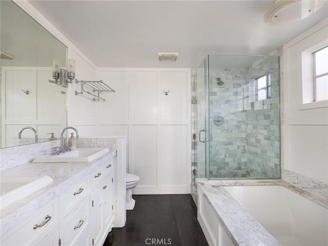 full bathroom featuring toilet, vanity, plus walk in shower, and hardwood / wood-style floors