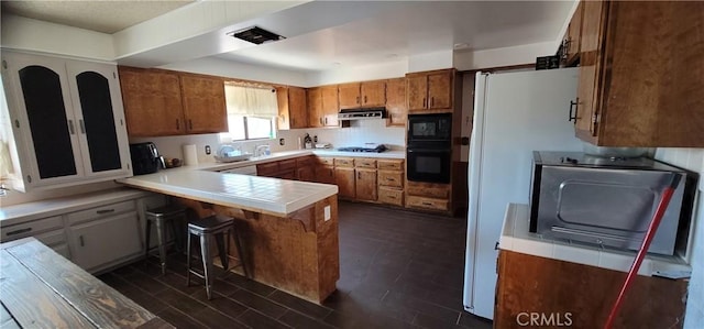 kitchen with sink, kitchen peninsula, a kitchen breakfast bar, and black appliances