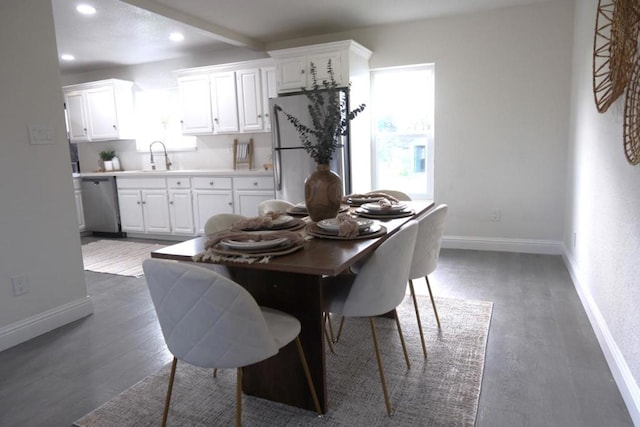 dining space with dark wood-type flooring, sink, and beam ceiling