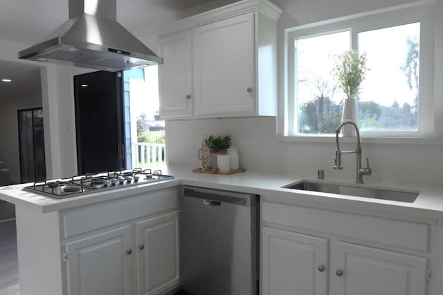 kitchen featuring sink, appliances with stainless steel finishes, white cabinets, island exhaust hood, and kitchen peninsula