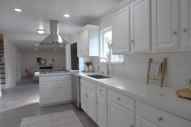 kitchen with sink, white cabinetry, stainless steel appliances, island exhaust hood, and kitchen peninsula