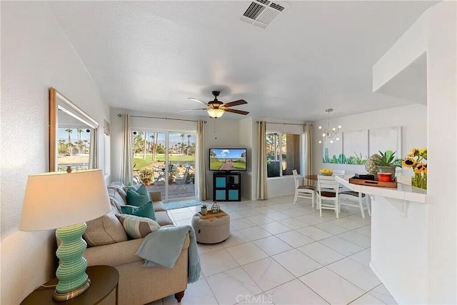 tiled living room featuring ceiling fan with notable chandelier