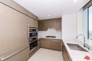 kitchen with double oven, sink, gas stovetop, and plenty of natural light