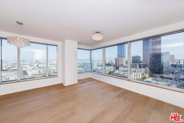 spare room featuring a chandelier and hardwood / wood-style floors