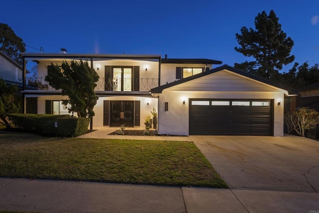 modern home featuring a garage, a balcony, and a front lawn