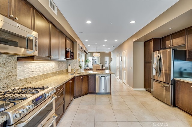 kitchen featuring light tile patterned floors, stainless steel appliances, tasteful backsplash, light stone countertops, and kitchen peninsula