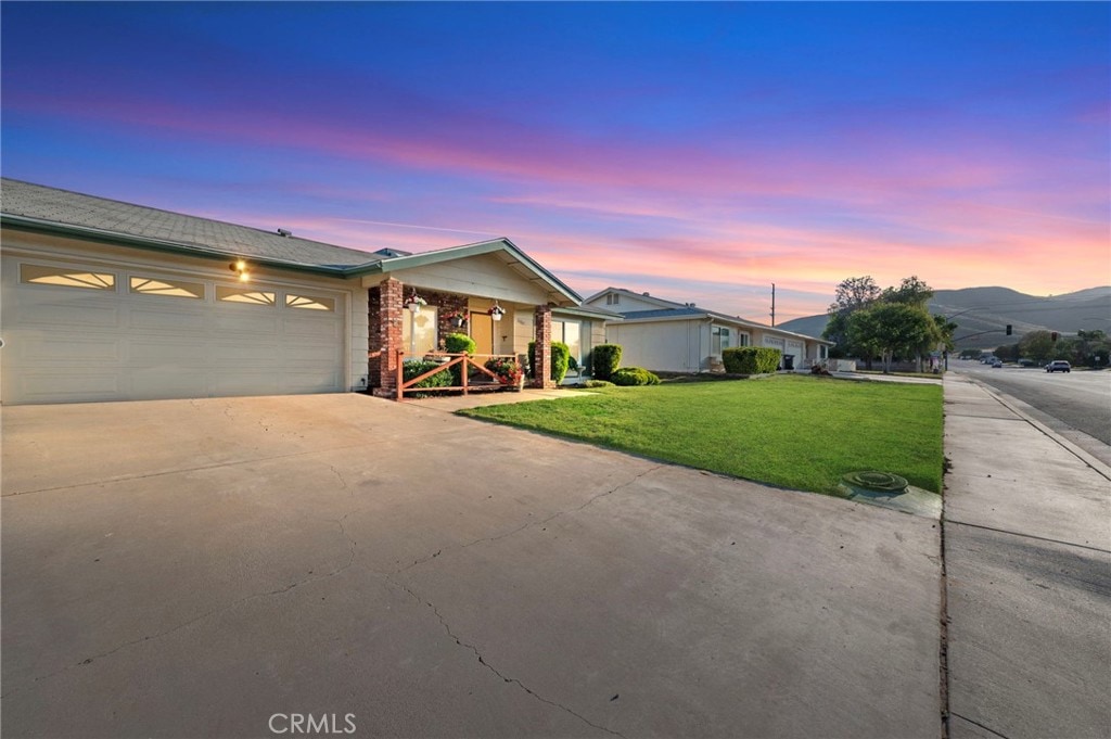 ranch-style home with a garage, a mountain view, and a lawn