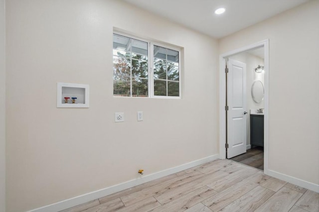 clothes washing area with hookup for an electric dryer, hookup for a washing machine, and light wood-type flooring