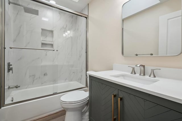 full bathroom with vanity, hardwood / wood-style floors, shower / bath combination with glass door, and toilet