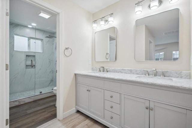 bathroom with wood-type flooring, toilet, vanity, and walk in shower