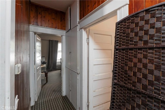 hallway with carpet floors and wood walls