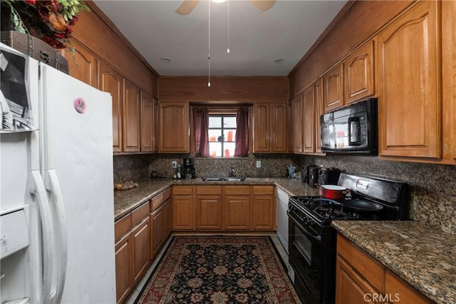 kitchen with dark stone countertops, sink, decorative backsplash, and black appliances