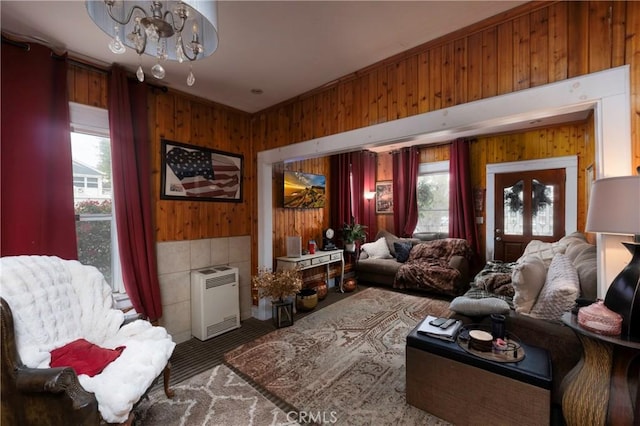 interior space with plenty of natural light, heating unit, a notable chandelier, and wood walls