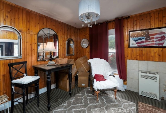 living area with dark colored carpet, heating unit, a chandelier, and wood walls