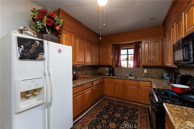 kitchen featuring tasteful backsplash, light stone countertops, sink, and black appliances