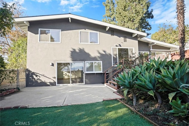 rear view of property with stairs, a patio, fence, and stucco siding