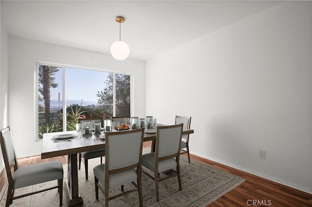 dining space with baseboards and wood finished floors