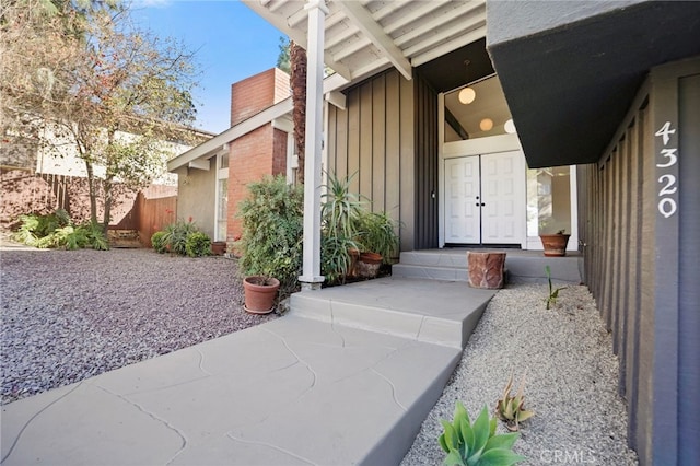 property entrance with board and batten siding and fence