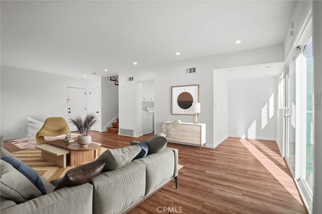 living room with recessed lighting, separate washer and dryer, visible vents, stairs, and light wood-type flooring