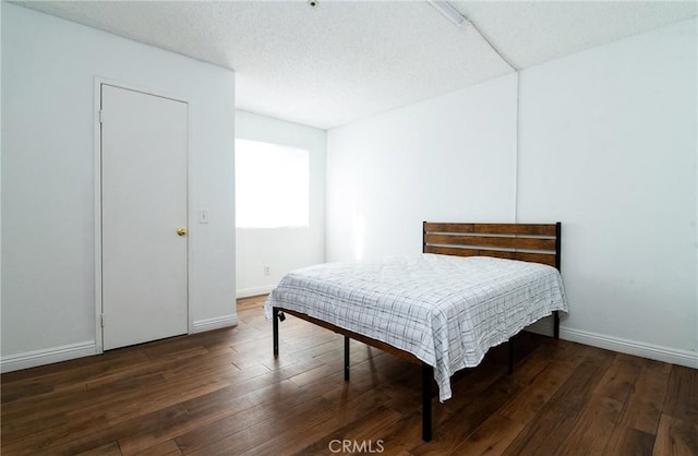 bedroom with dark hardwood / wood-style floors and a textured ceiling