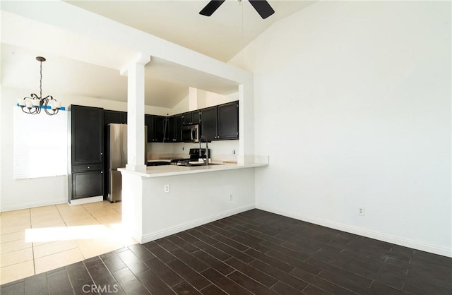 kitchen with vaulted ceiling, hanging light fixtures, appliances with stainless steel finishes, dark hardwood / wood-style flooring, and kitchen peninsula