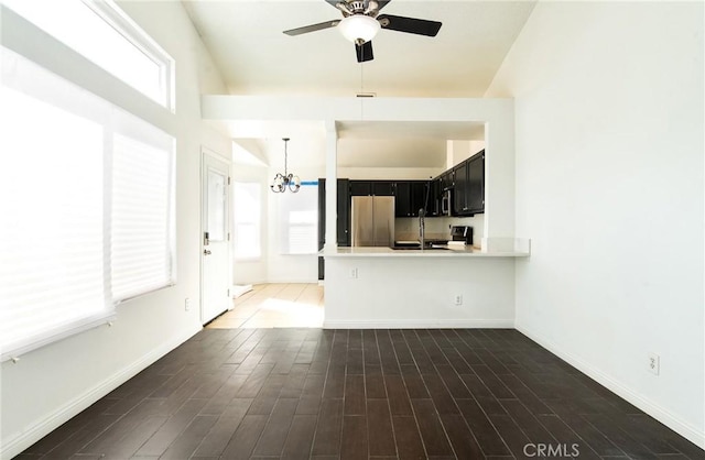 unfurnished living room featuring ceiling fan with notable chandelier and dark hardwood / wood-style floors