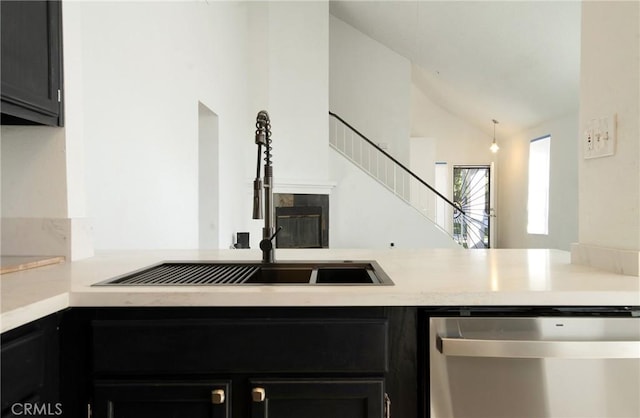 kitchen with lofted ceiling, sink, dishwasher, a fireplace, and kitchen peninsula