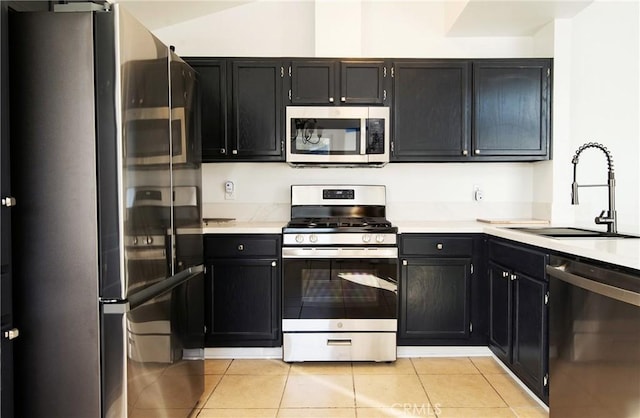 kitchen with sink, light tile patterned floors, vaulted ceiling, and appliances with stainless steel finishes