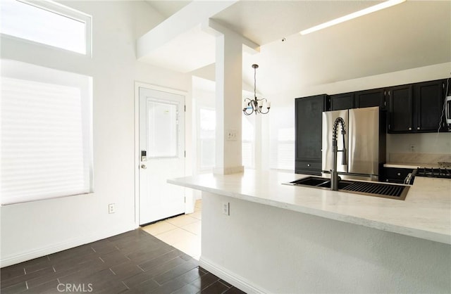 kitchen featuring appliances with stainless steel finishes, decorative light fixtures, wood-type flooring, a notable chandelier, and kitchen peninsula