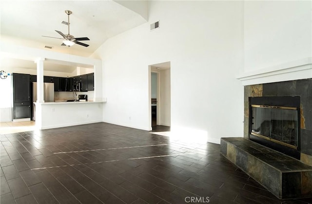 unfurnished living room with ceiling fan, high vaulted ceiling, dark wood-type flooring, and a fireplace