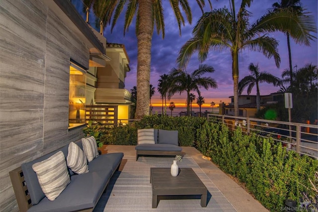 patio terrace at dusk with an outdoor living space and a balcony