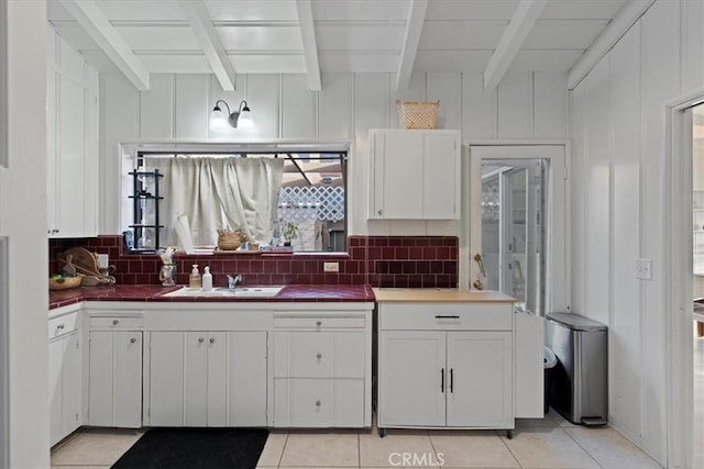 kitchen with tasteful backsplash, sink, beam ceiling, and white cabinets