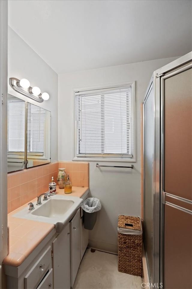 bathroom featuring walk in shower, vanity, and decorative backsplash