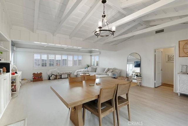 dining space with lofted ceiling with beams, a chandelier, and light hardwood / wood-style floors