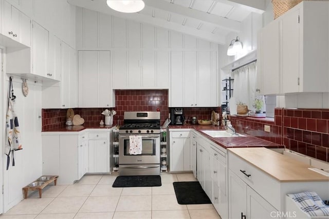 kitchen with tasteful backsplash, stainless steel range with gas cooktop, vaulted ceiling with beams, and white cabinets