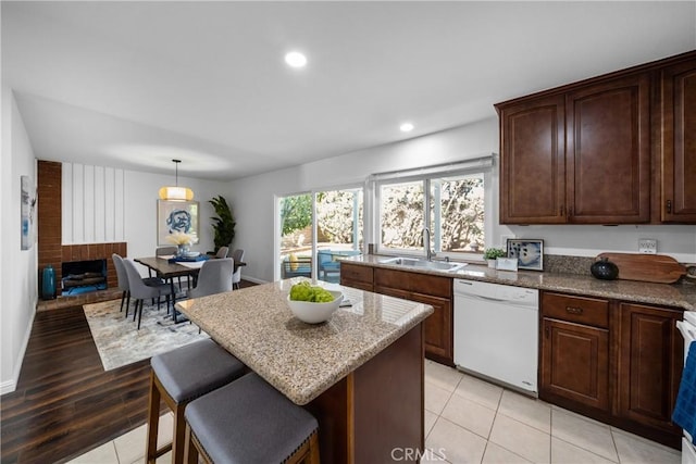 kitchen with a kitchen island, dishwasher, sink, hanging light fixtures, and dark brown cabinets