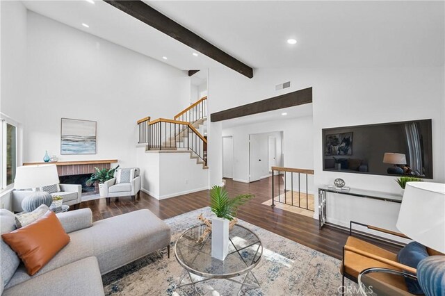 living room with a fireplace, dark hardwood / wood-style flooring, high vaulted ceiling, and beam ceiling