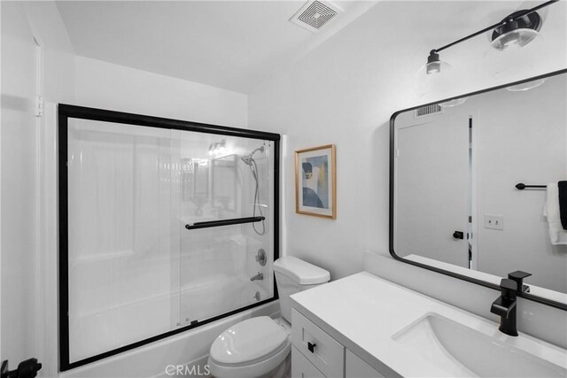 full bathroom featuring toilet, vanity, and bath / shower combo with glass door