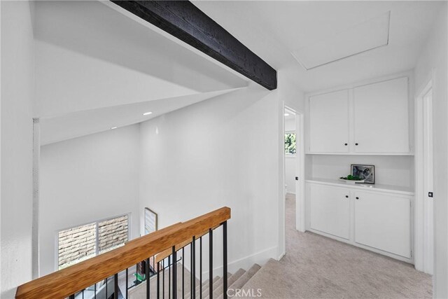 hallway featuring beamed ceiling and light colored carpet