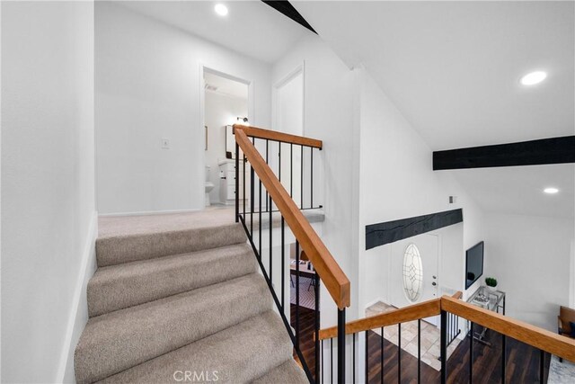 stairway with lofted ceiling with beams and hardwood / wood-style floors