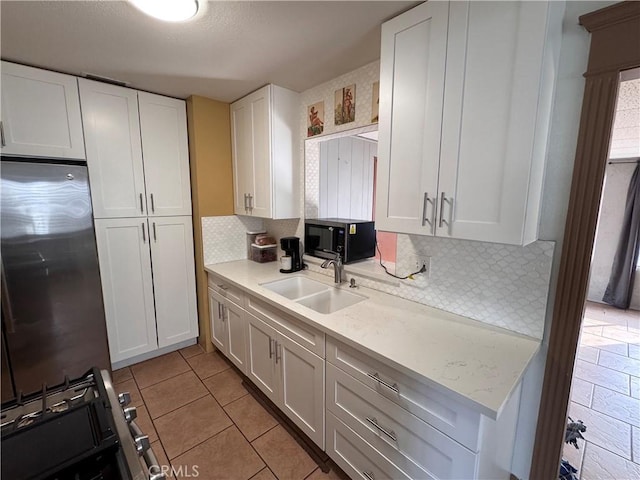 kitchen with white cabinetry, sink, light tile patterned floors, and backsplash