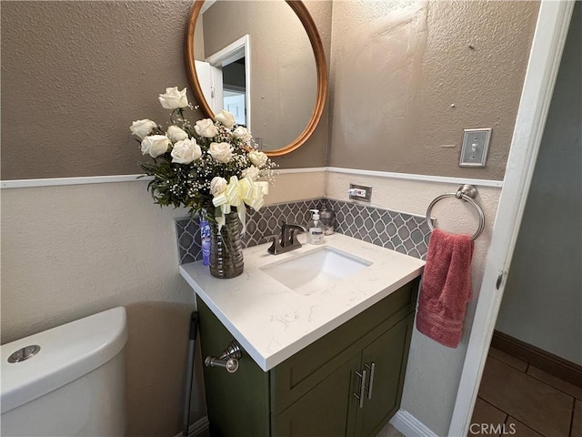 1704 Sunrise Rd, Barstow, CA 92311 - bathroom featuring toilet, vanity, tile patterned floors, decorative backsplash, and a textured wall