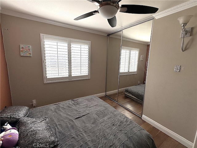 bedroom with dark hardwood / wood-style flooring, crown molding, a closet, and ceiling fan