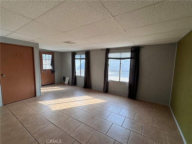 empty room with light tile patterned floors and a drop ceiling