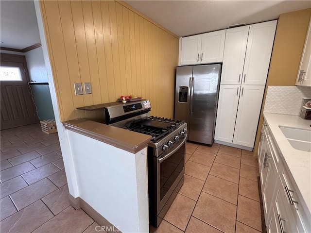 1704 Sunrise Rd, Barstow, CA 92311 - kitchen featuring appliances with stainless steel finishes, white cabinets, light tile patterned floors, wood walls, and a sink
