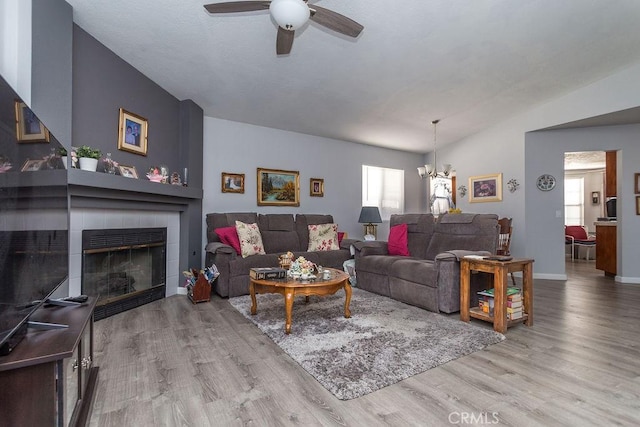 living room with light hardwood / wood-style flooring, a fireplace, plenty of natural light, and vaulted ceiling