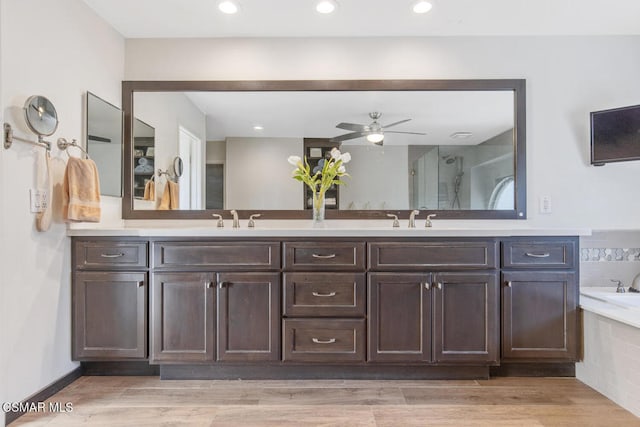 bathroom featuring vanity, tiled tub, wood-type flooring, and ceiling fan